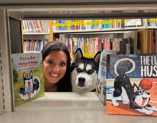 Bethany O'Brien and Jonathan the Husky peeking through library shelves beside the Dairy Bar Disaster and The Lucky Husky books